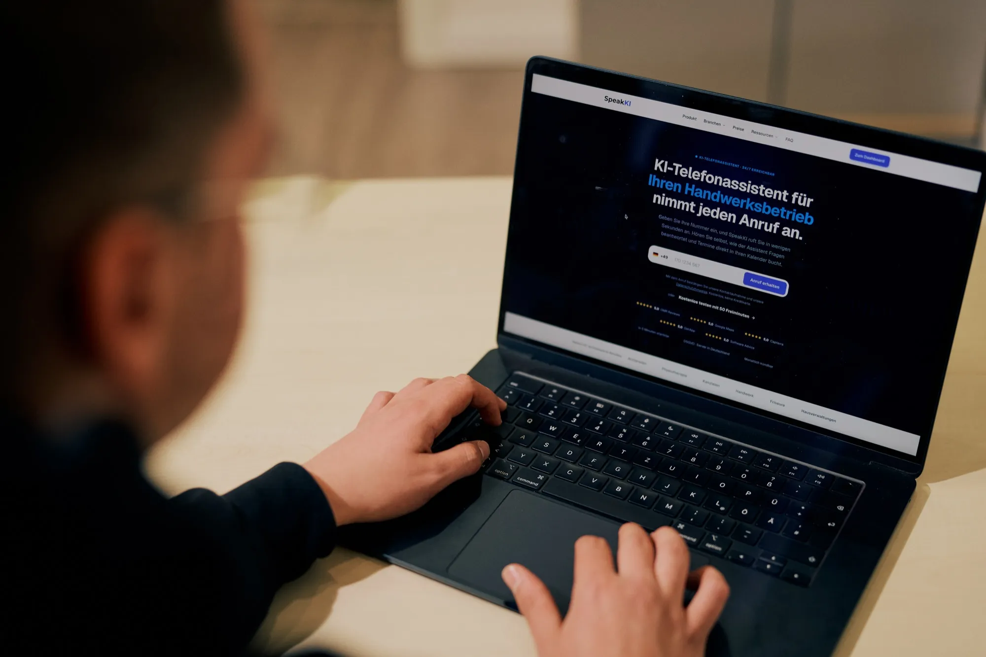 Blick über die Schulter auf einen Laptop mit der SpeakKI-Website für Handwerksbetriebe